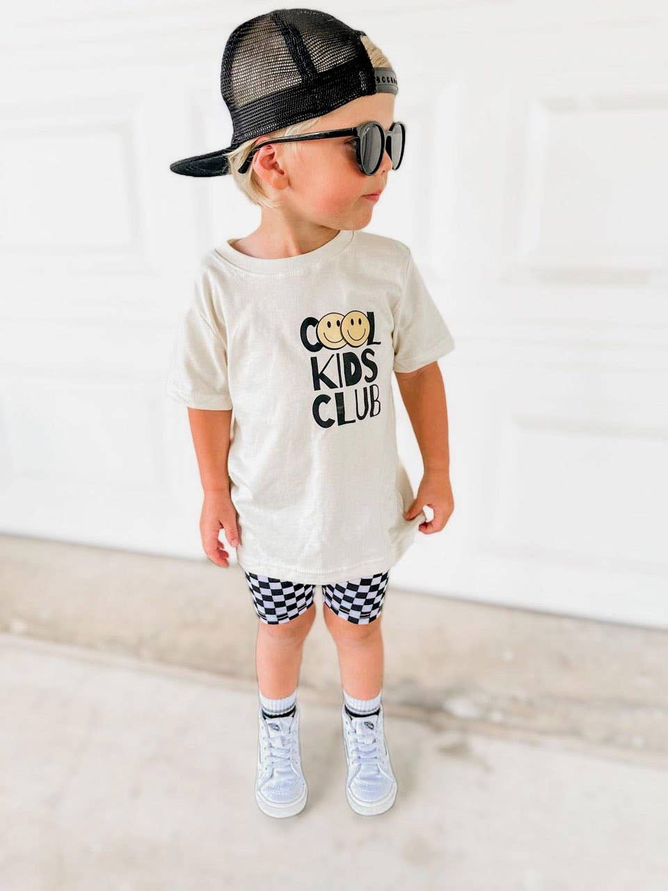 Young boy wearing stylish 'Cool Kids Club' t-shirt and checkered shorts from the Kids' Collection at J&J Shop Online, owned by 90 Day Fiancé stars Juan and Jessica