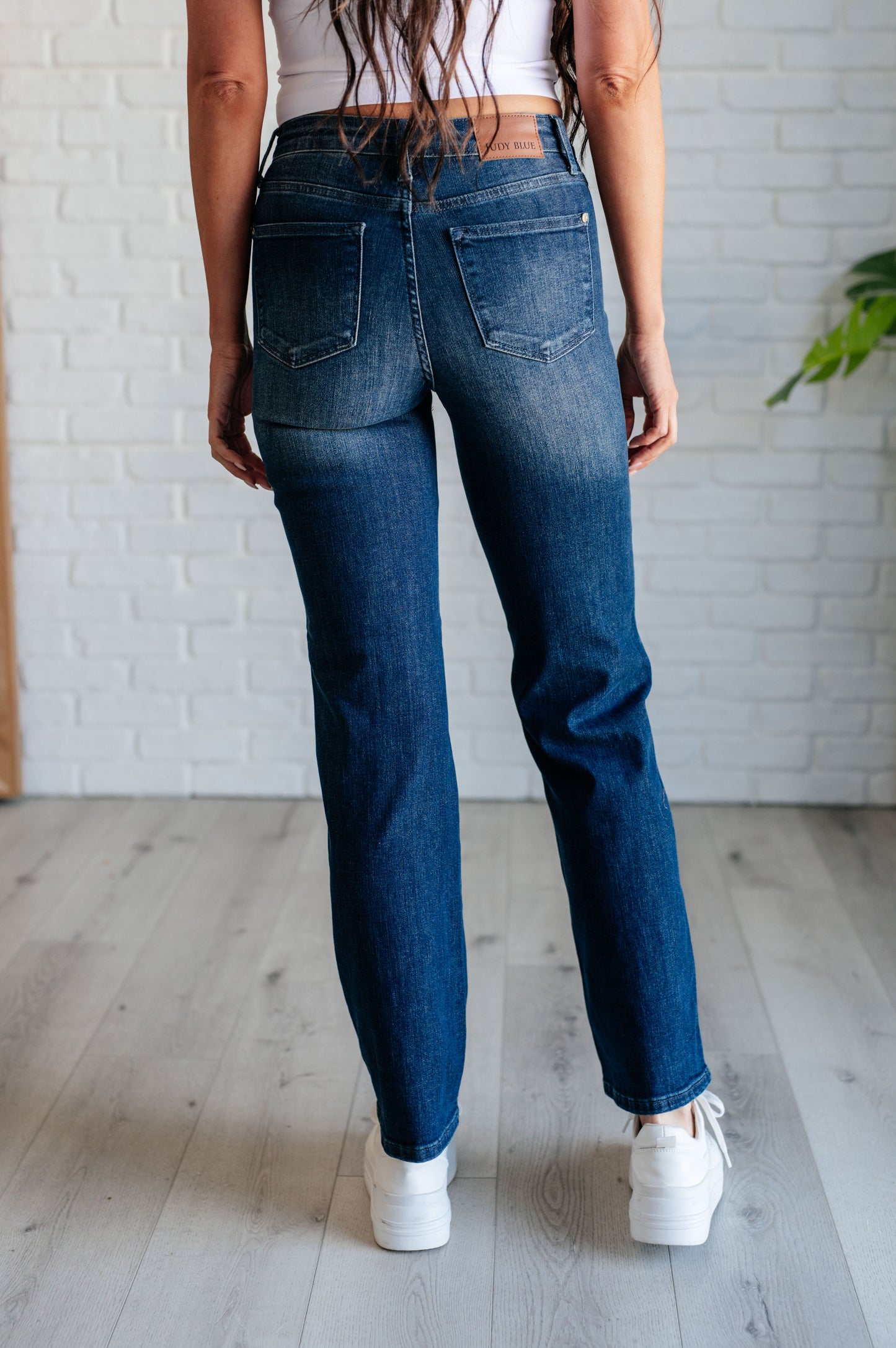 Model sitting while wearing the Muriel Mid Rise Control Top Classic Straight Jeans from J&J Shop Online, demonstrating comfort and fit.