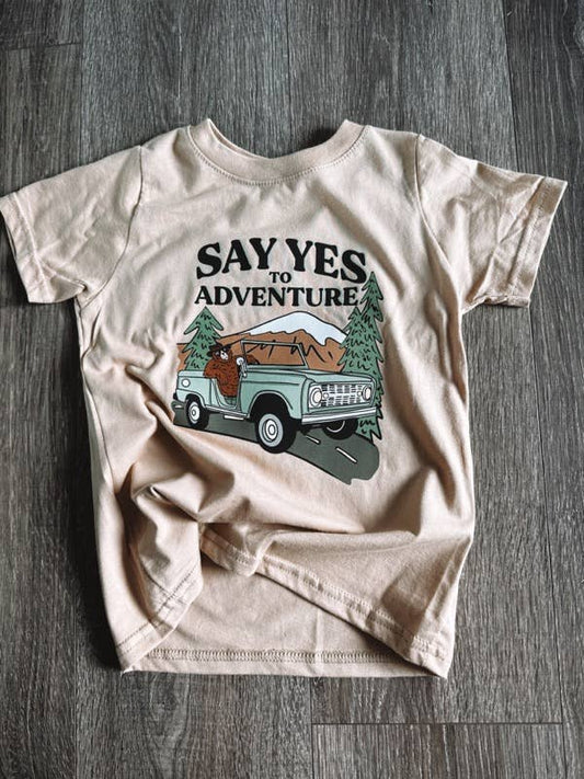 Say Yes to Adventure Kids T-Shirt featuring a scenic outdoor graphic with a car and mountains, perfect for trendy kids' summer clothing - J&J Shop Online owned by super stars juan and jessica from 90 day fiance 