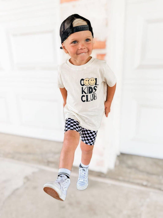 Young boy wearing stylish 'Cool Kids Club' t-shirt and checkered shorts from the Kids' Collection at J&J Shop Online, owned by 90 Day Fiancé stars Juan and Jessica