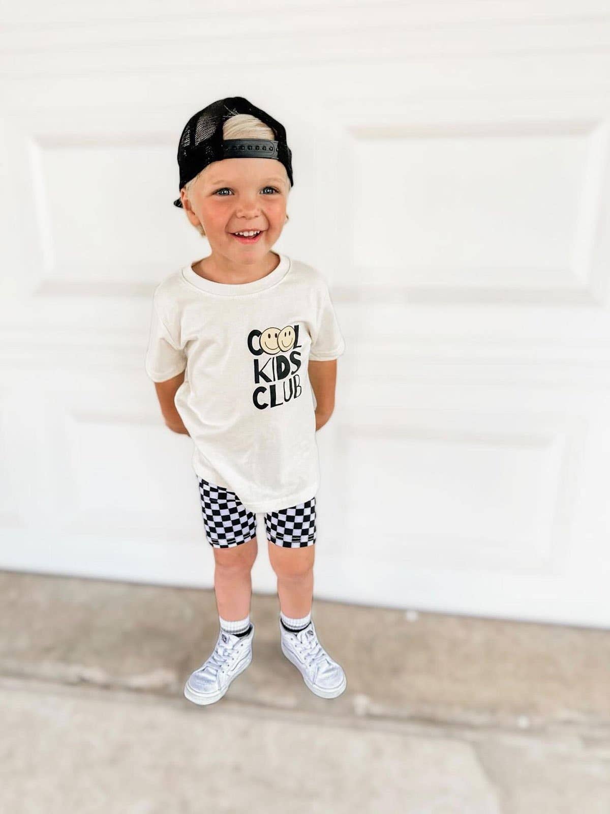 Young boy wearing stylish 'Cool Kids Club' t-shirt and checkered shorts from the Kids' Collection at J&J Shop Online, owned by 90 Day Fiancé stars Juan and Jessica